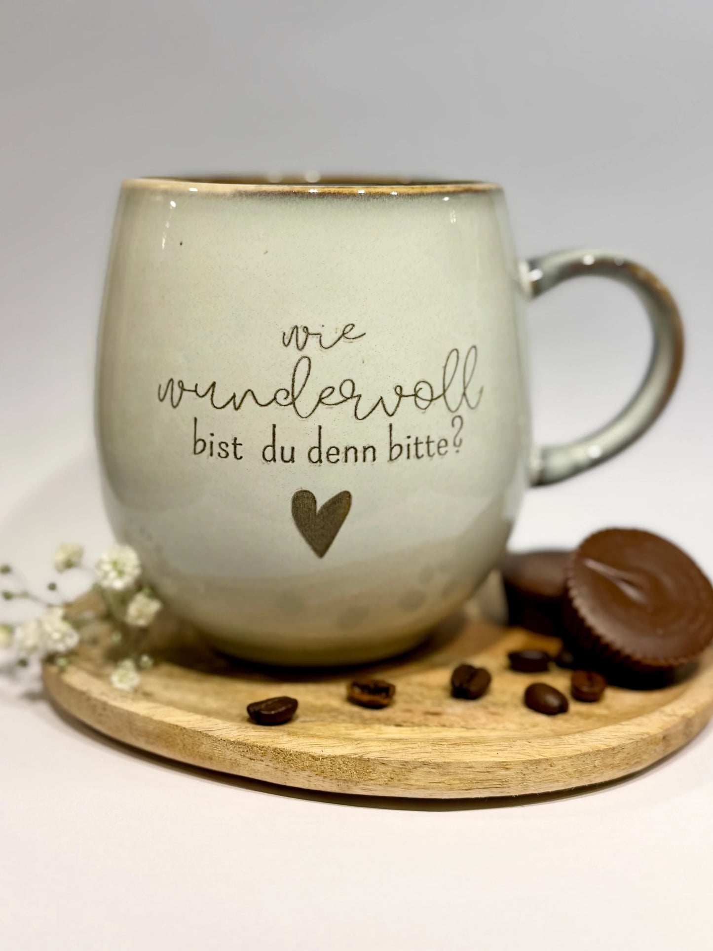 Personalisierte Keramiktasse mit Gravur „wie wundervoll bist du denn bitte?“, auf Holzbrett mit Schokolade und Kaffeebohnen, lieblingsschuppen.de Geschenkidee