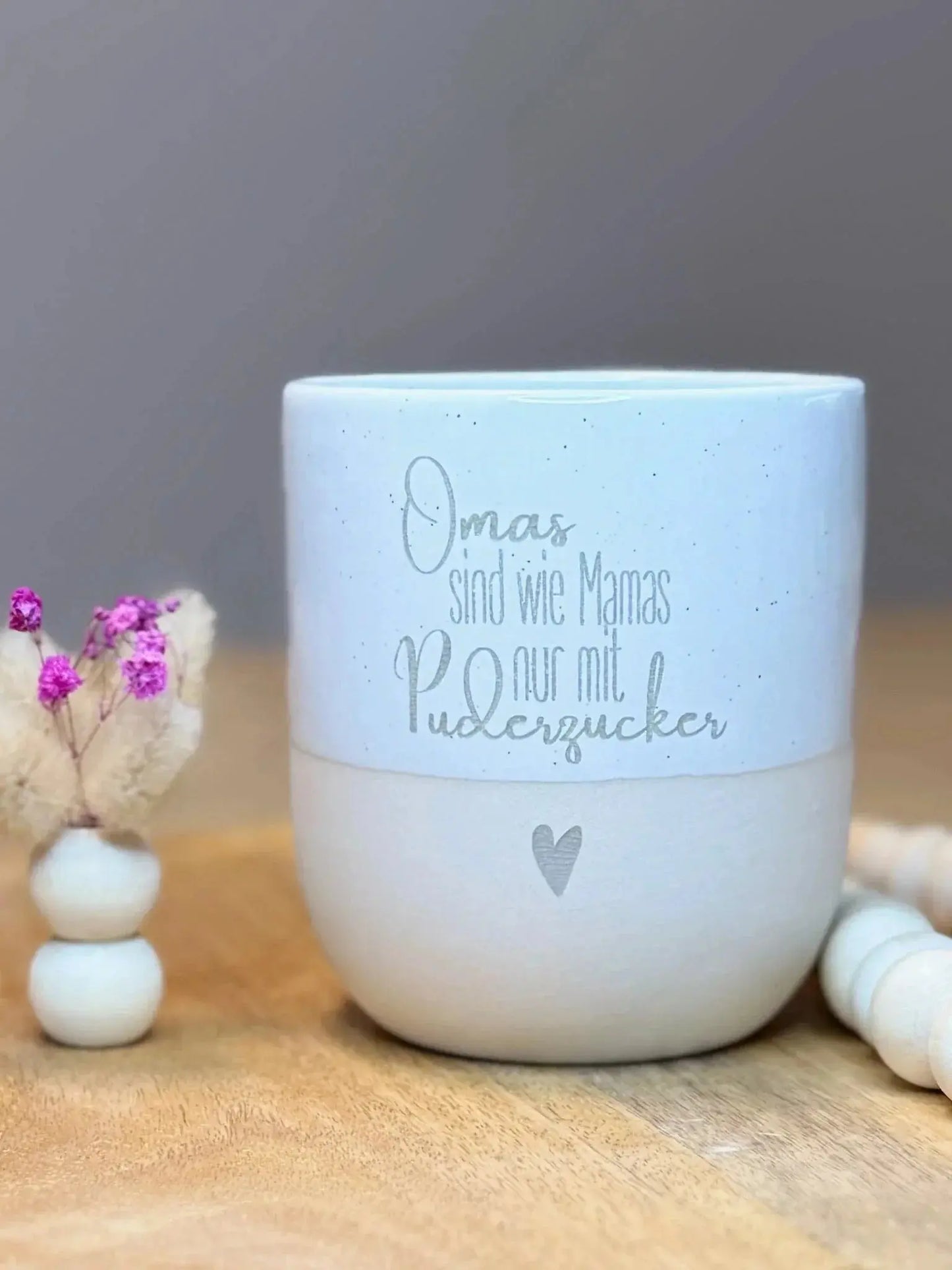 Personalisierte Tasse mit Gravur 'Omas sind wie Mamas nur mit Puderzucker' auf Holzuntergrund