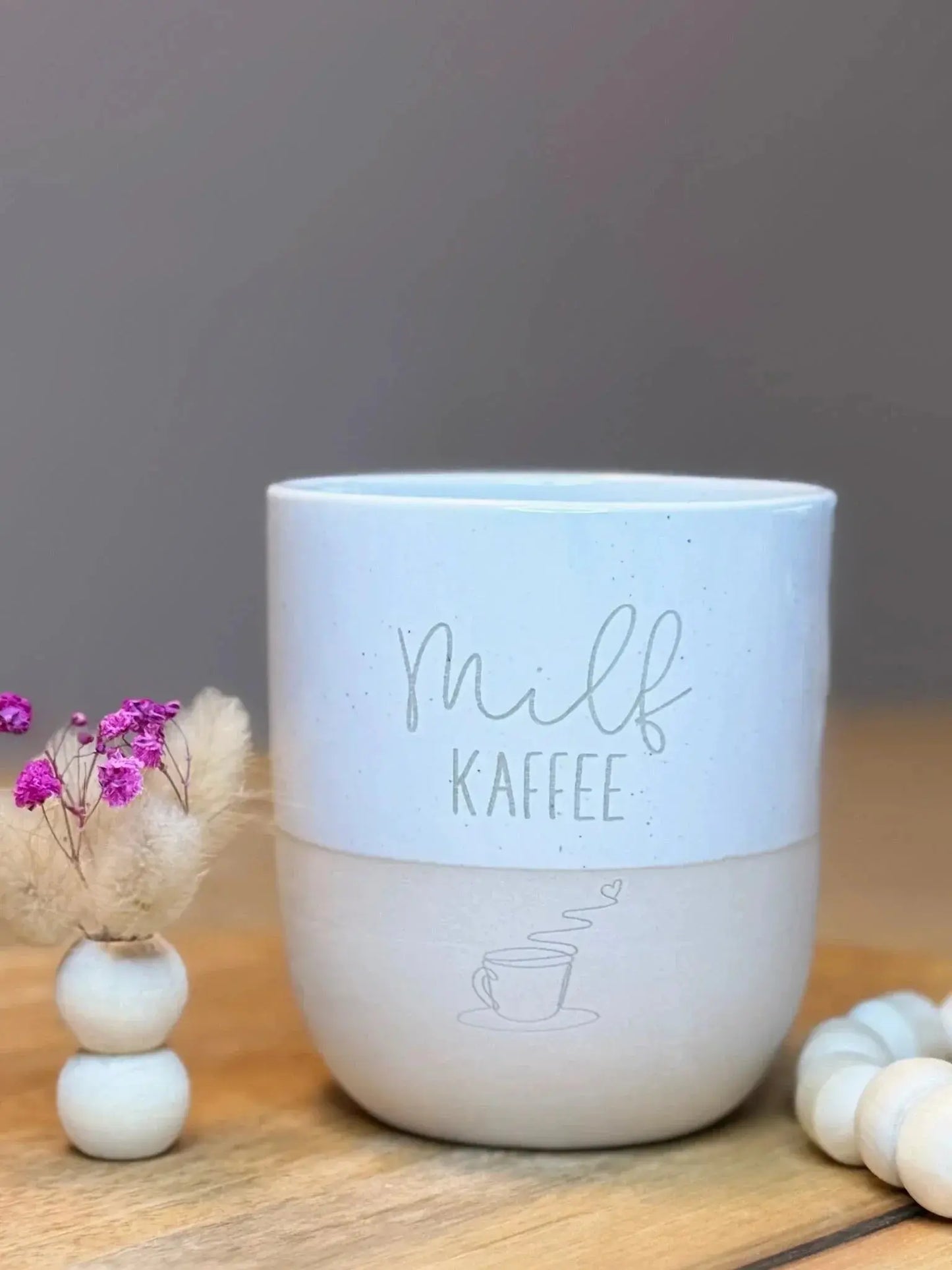 Personalisierte Kaffeetasse mit Gravur 'milf KAFFEE' auf Holz, neben Trockenblumen, Lieblingsschuppen.de
