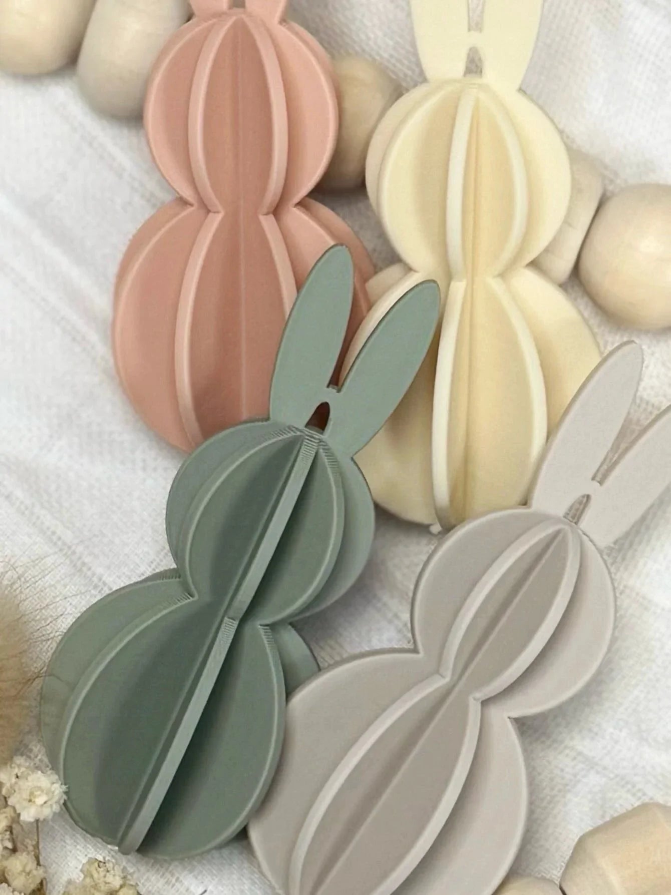 Deko Osterhasen aus Holz in Pastellfarben auf weißem Stoff, personalisierte Geschenkidee