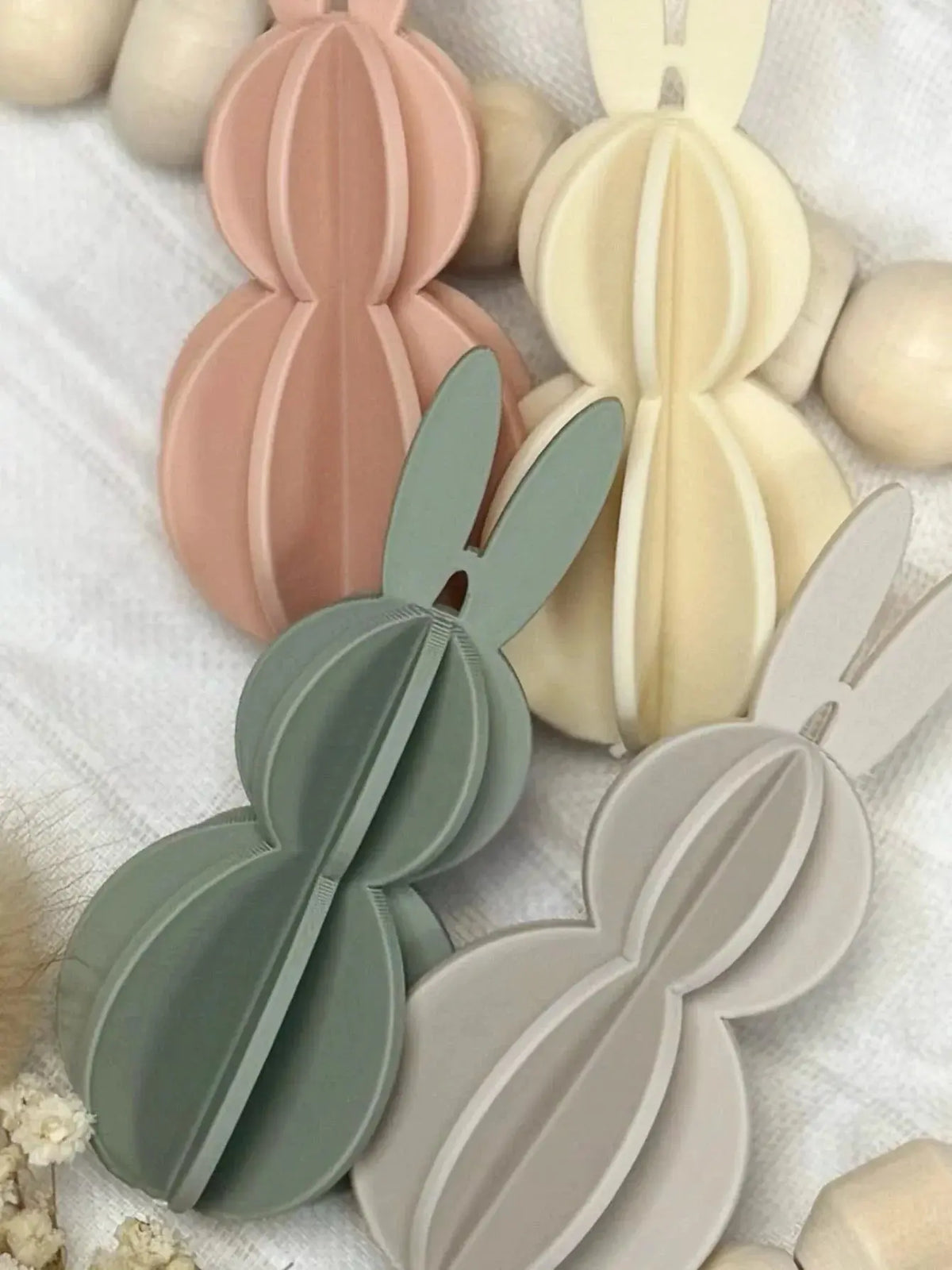 Deko Osterhasen aus Holz in Pastellfarben auf weißem Stoff, personalisierte Geschenkidee