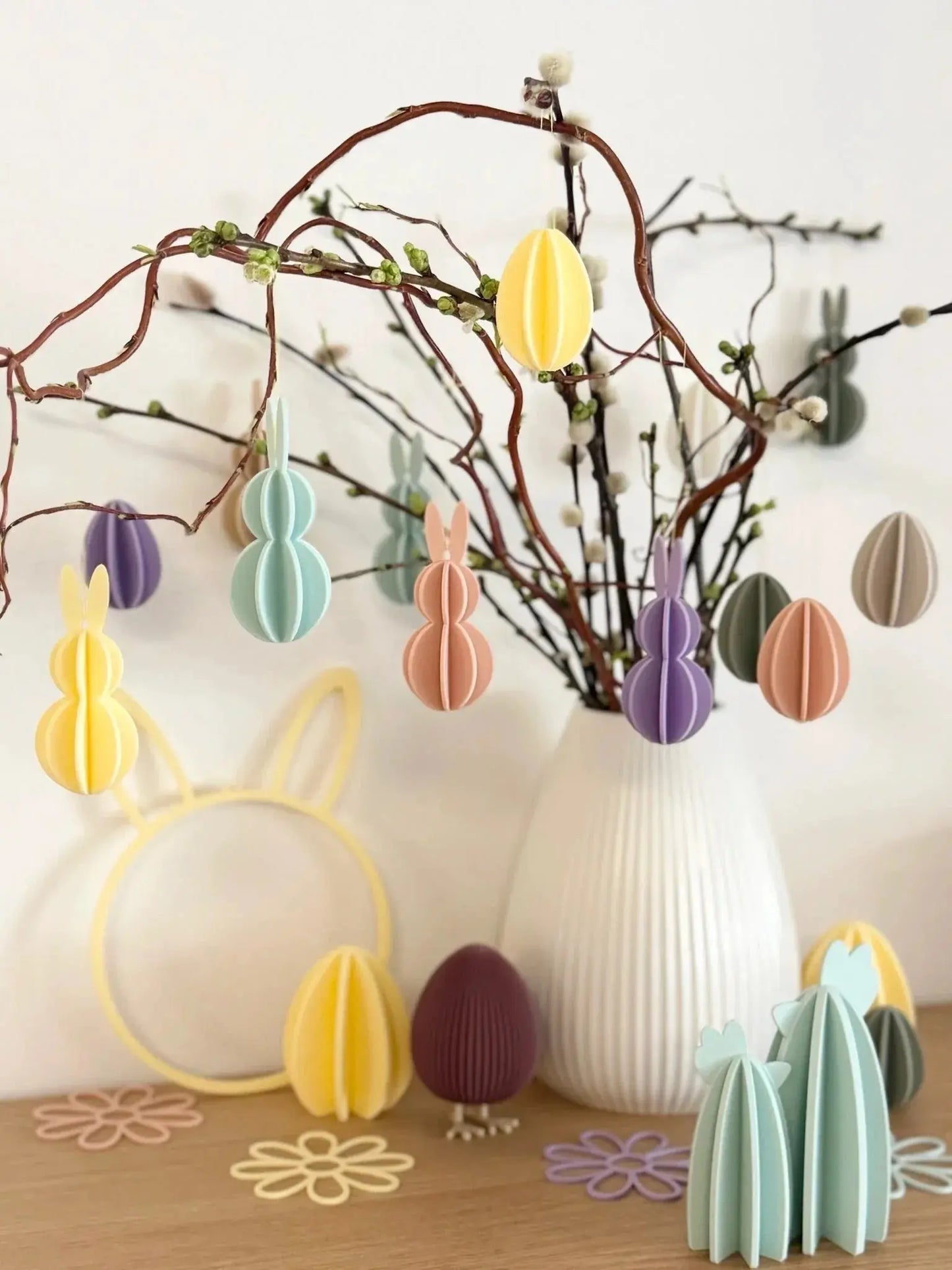 Frühlingshafter Osterstrauch mit bunten, personalisierten Deko-Anhängern und Eiern in Vase