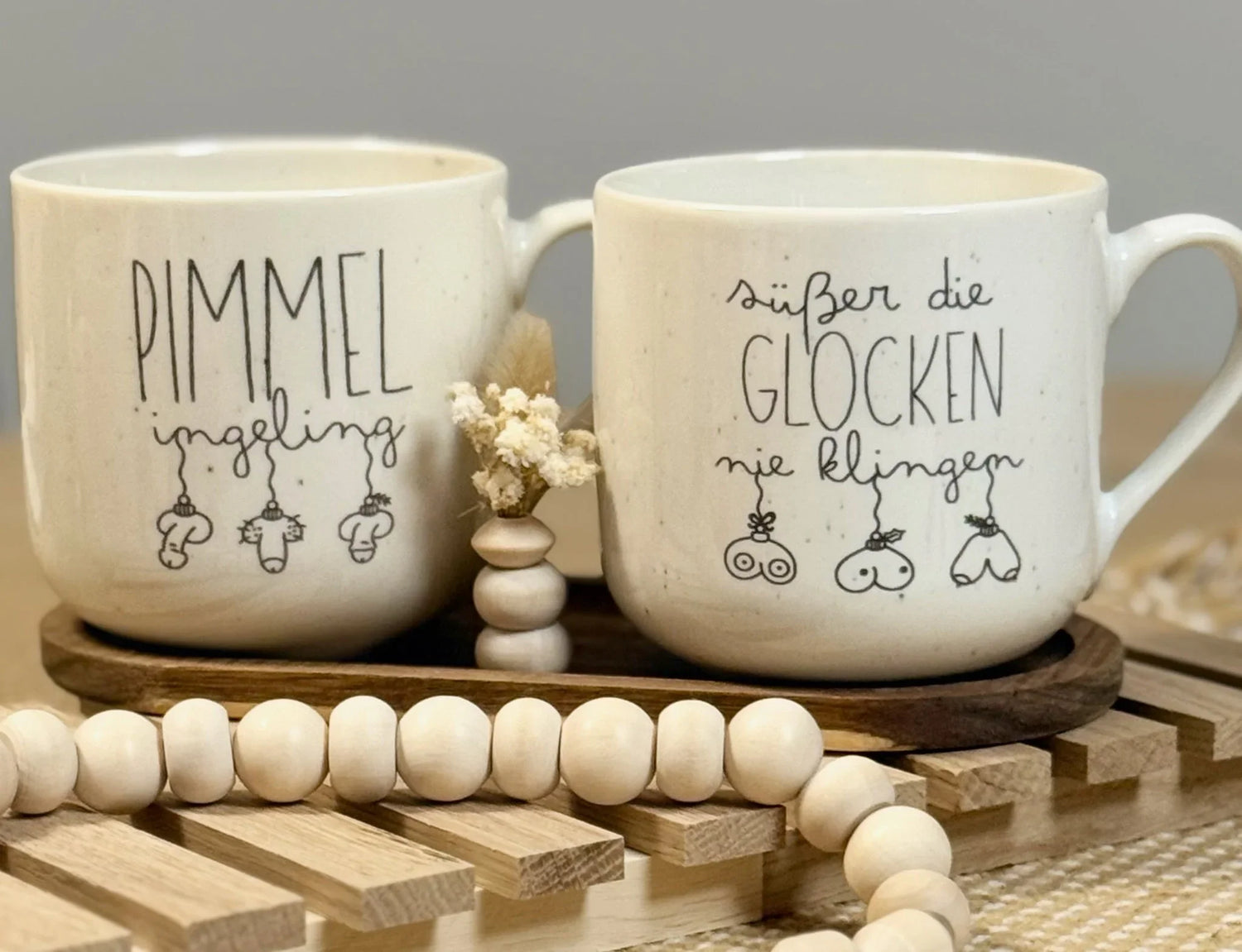Zwei Keramik-Tassen mit witzigen, handbeschrifteten Gravuren und Illustrationen, auf Holzunterlage, Geschenkidee von Lieblingsschuppen.de