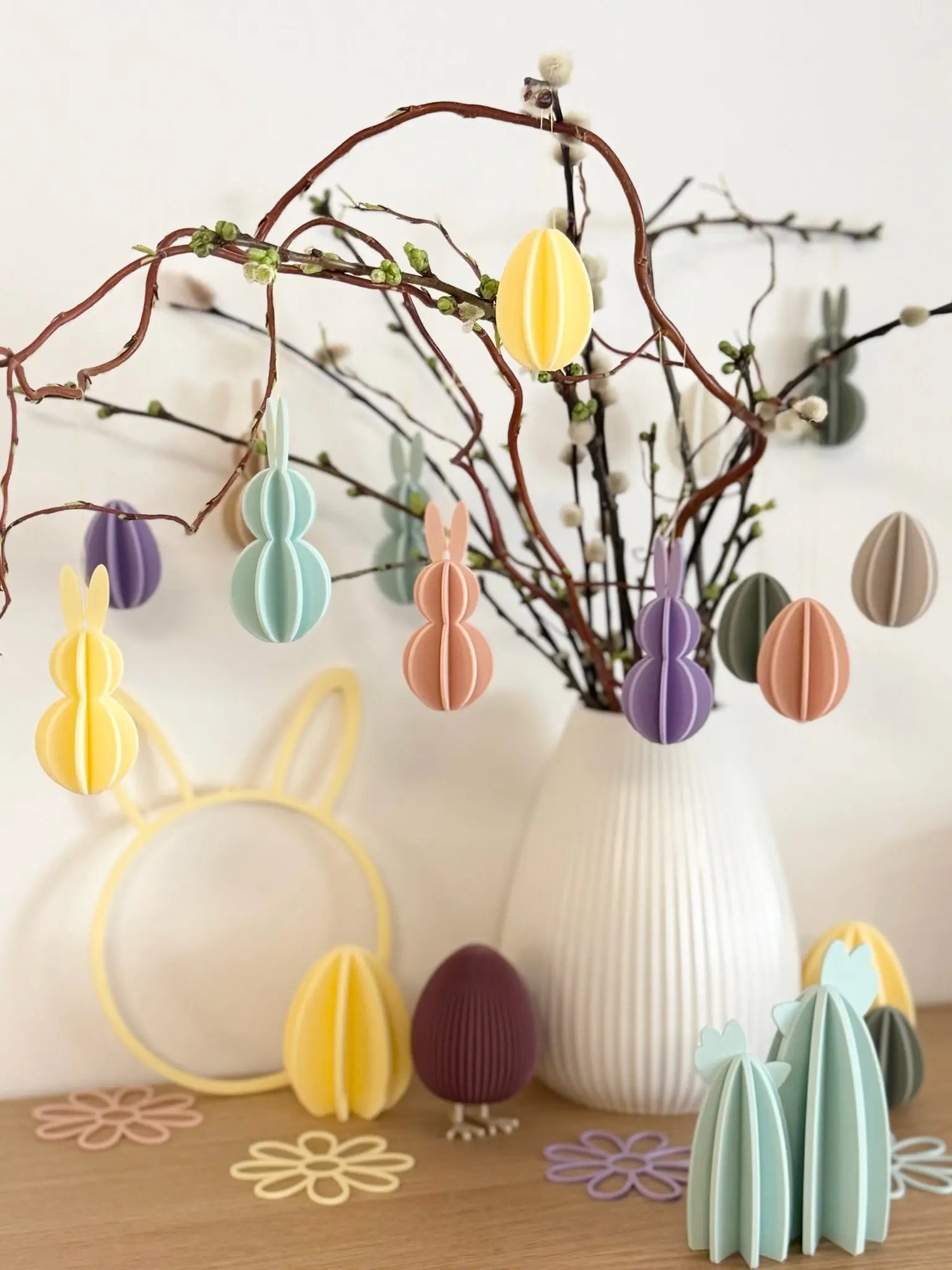 Dekorativer Osterstrauß mit buntem Anhängern aus Papier und Frühlingszweigen in weißer Vase, personalisierte Geschenkideen von Lieblingsschuppen.de