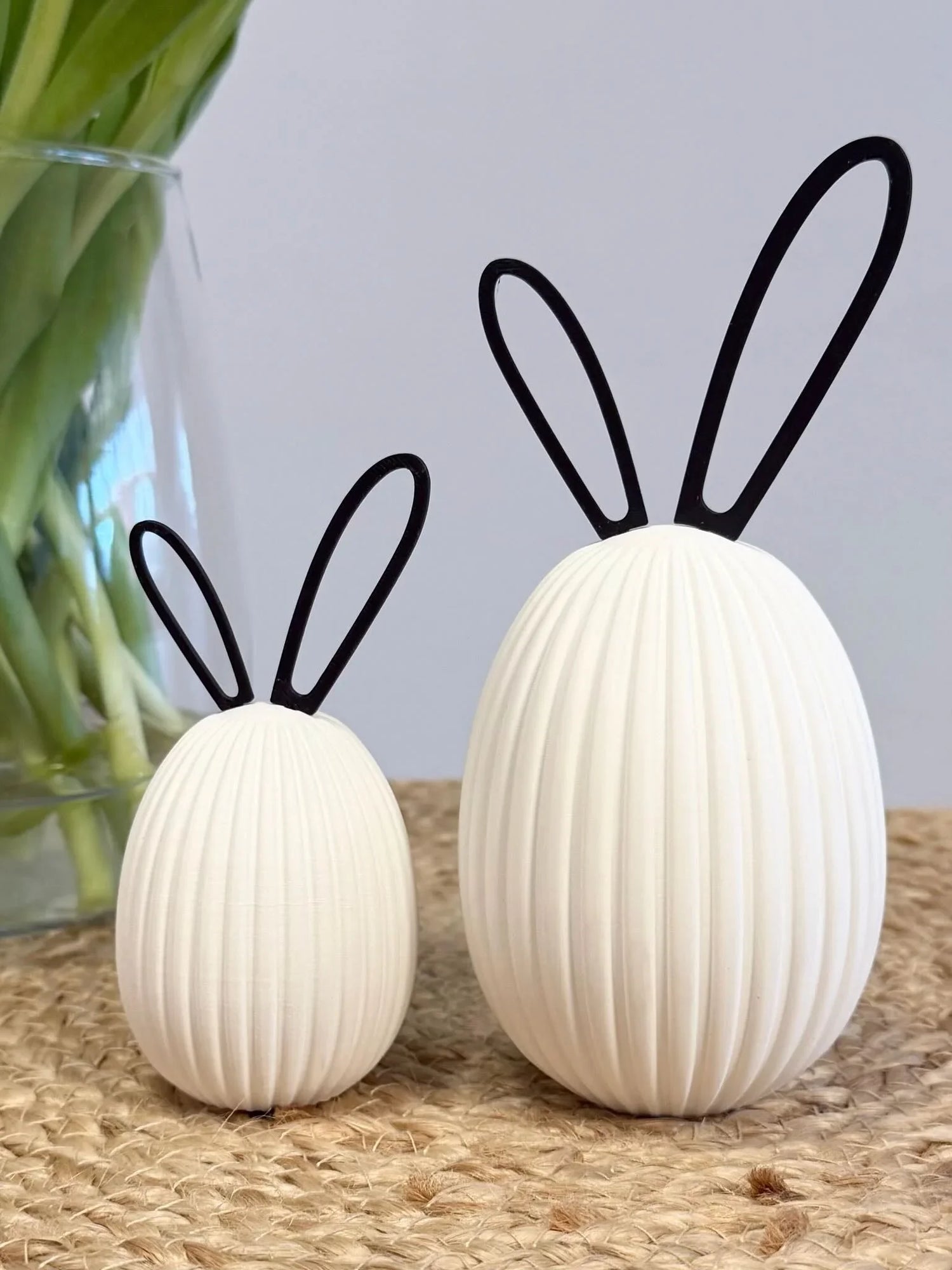 Zwei weiße, gerillte Deko-Eier mit Hasenohren aus Draht auf Juteteppich, Frühlingsdeko Geschenk