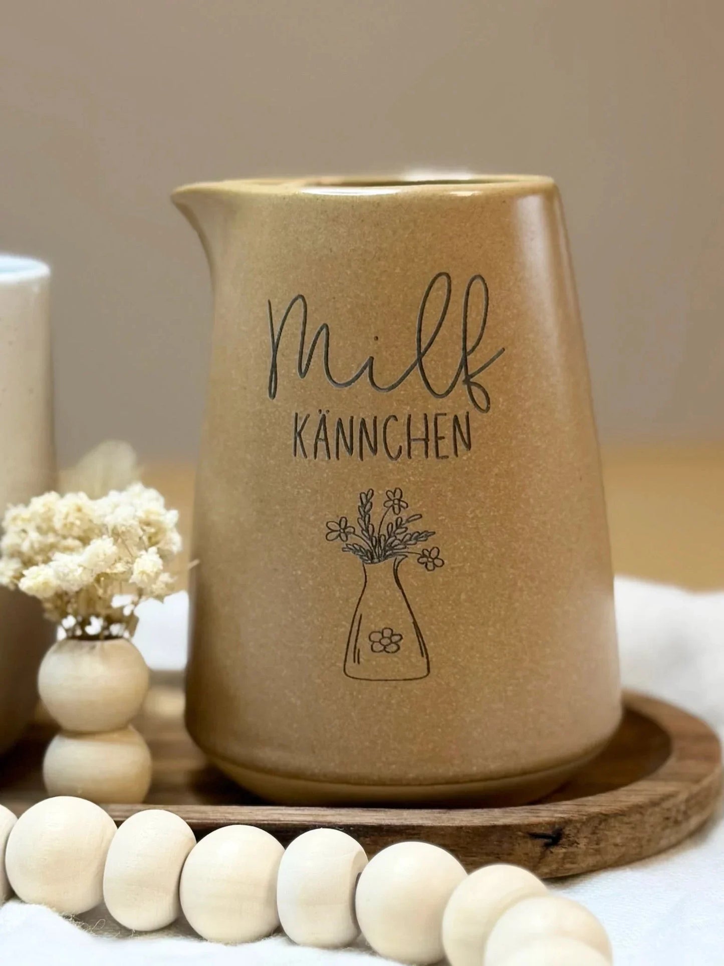 Personalisierte Milchkanne aus Keramik mit Blumen-Illustration und Gravur, dekorativ auf Tablett